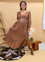 Load image into Gallery viewer, Model is wearing the Logan dress with western inspired accessories and a western inspired backdrop. 
