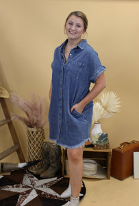 Denim button down dress with western inspired backdrop. Model has hands in pockets