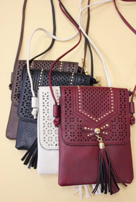 Image shows a faux leather crossbody bag with tassle in a western style, available in four colors, brown, burgundy, black and cream.