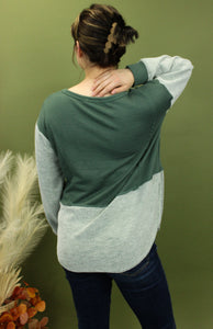 Model is wearing a green and grey colorblock long sleeve top 
