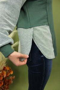 Model is wearing a green and grey colorblock long sleeve top 