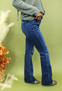 Model is wearing dark wash boot cut jeans. 