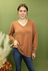 Model is wearing an oversized rust colored sweater. 