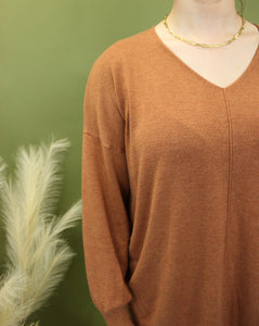 Model is wearing an oversized rust colored sweater. 