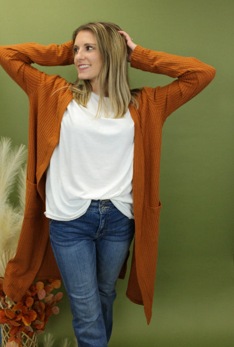 Model is wearing a longline rusty orange waffle knit cardigan. 