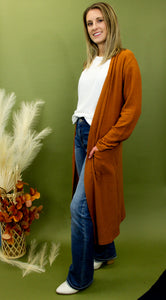 Model is wearing a longline rusty orange waffle knit cardigan. 