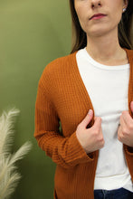 Load image into Gallery viewer, Model is wearing a longline rusty orange waffle knit cardigan. 
