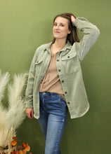 Load image into Gallery viewer, Model is wearing a moss green corduroy jacket in front of a fall backdrop 
