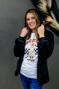 Model is wearing a graphic tee shirt featuring a ghost riding a skateboard. 