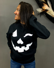 Load image into Gallery viewer, Model is wearing a black crew neck sweatshirt with a jack o lantern graphic. 
