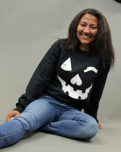 Model is wearing a black crew neck sweatshirt with a jack o lantern graphic. 