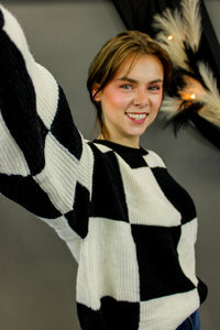 Model is wearing an oversized checkered sweater. 