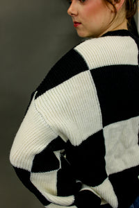 Model is wearing an oversized checkered sweater. 