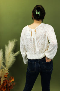 Model is wearing a white open knit sweater. 