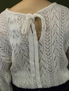 Model is wearing a white open knit sweater. 