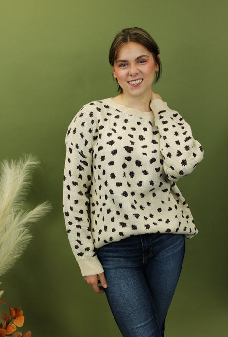 Model is weairng a cream color crew neck sweater with brown cheetah inspired print. 