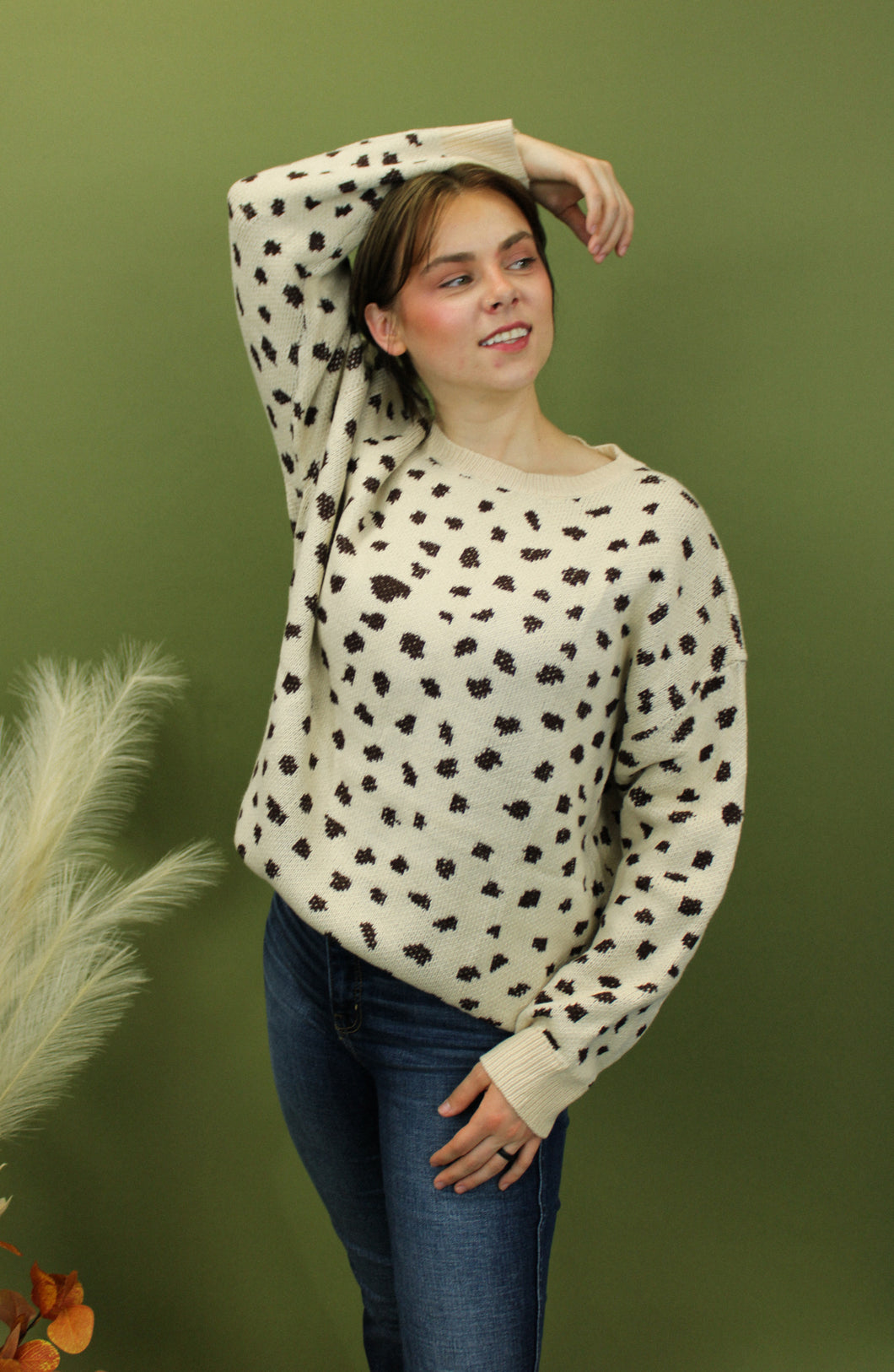 Model is weairng a cream color crew neck sweater with brown cheetah inspired print. 