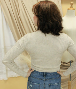 Model is wearing a slightly cropped neutral color sweater with a hint of sparkles. 