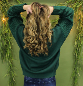 Model is wearing a green sweater in front of a festive background. 