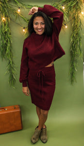 Model is wearing a burgundy sweater and sweater skirt set. 