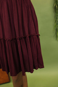 Model is wearing a burgundy dress.
