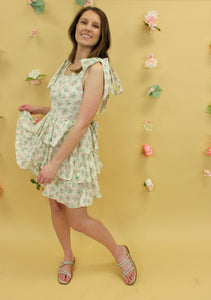 Model is wearing a cream feminine dress with pink and green florals.