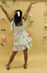Model is wearing a cream feminine dress with pink and green florals.