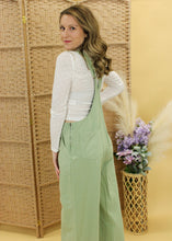 Load image into Gallery viewer, Model is wearing a light green overall with a white long sleeve top. 
