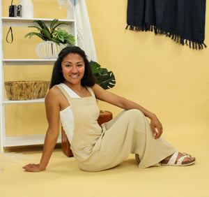 Model is wearing a beige jumpsuit. 