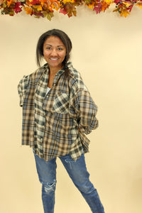 Model is wearing a plaid oversized button up shirt. 