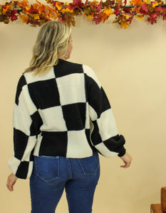 Model is wearing a black and white checkered sweater. 