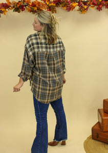 Model is wearing a plaid oversized button up shirt. 