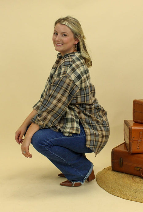 Model is wearing a plaid oversized button up shirt. 