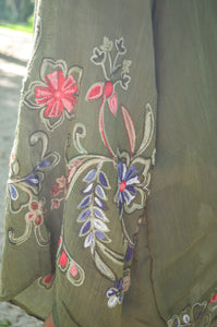 Model is wearing a green kimono with red and blue embroidered florals.