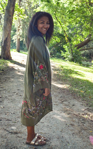Model is wearing a green kimono with red and blue embroidered florals.
