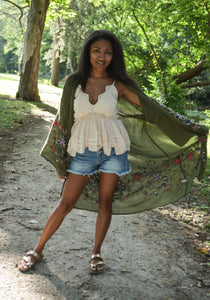 Model is wearing a green kimono with red and blue embroidered florals.